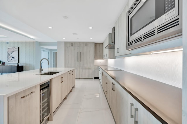 kitchen with sink, a large island, beverage cooler, wall chimney range hood, and stainless steel microwave