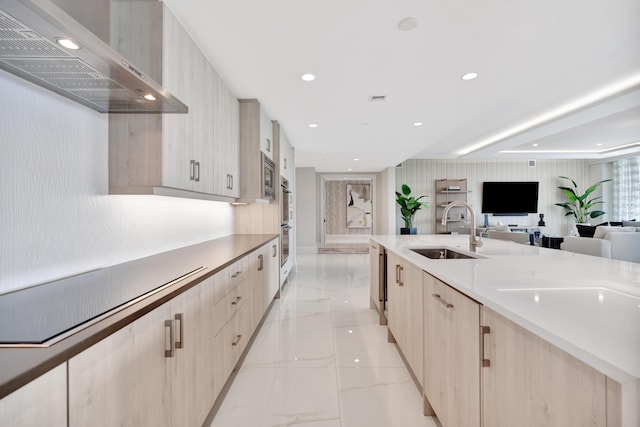 kitchen with stainless steel appliances, wall chimney range hood, light brown cabinets, and sink