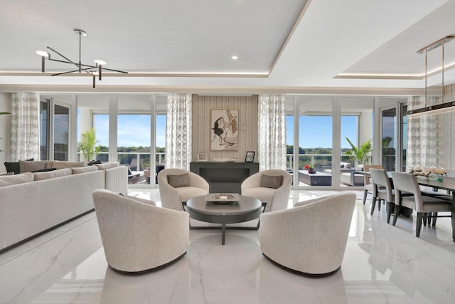 living room with a notable chandelier, a tray ceiling, a wealth of natural light, and a wall of windows