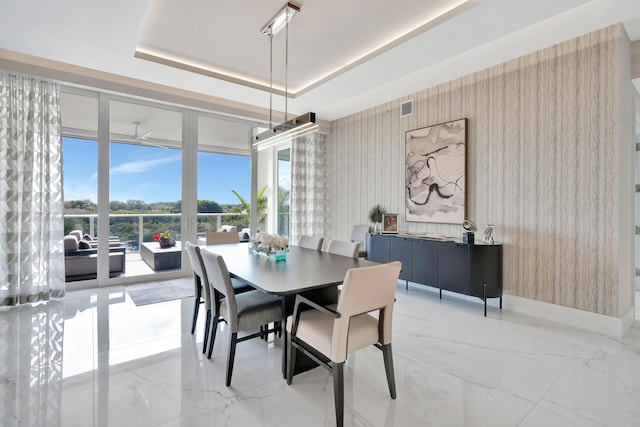 dining space with a wall of windows and a raised ceiling