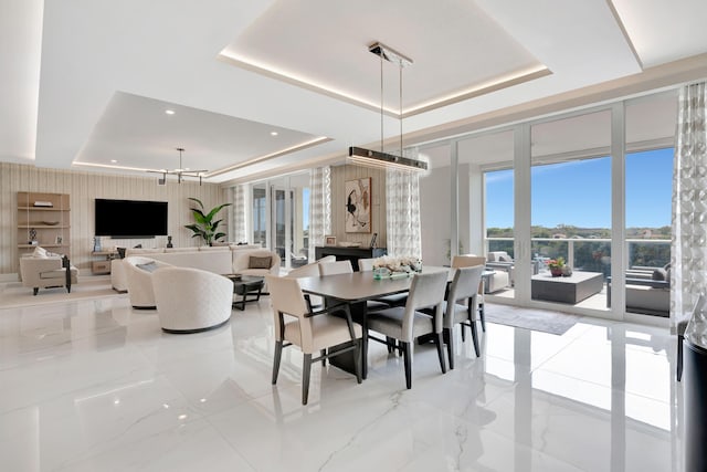 dining space with a notable chandelier and a raised ceiling