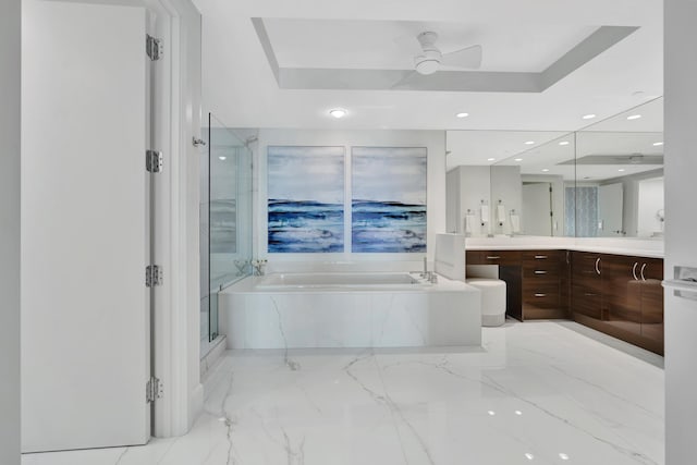 bathroom with vanity, ceiling fan, a tray ceiling, and separate shower and tub