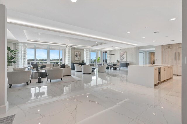 living room with a fireplace, a raised ceiling, and sink