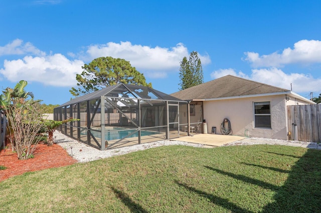 back of property with a yard, a fenced in pool, glass enclosure, and a patio area