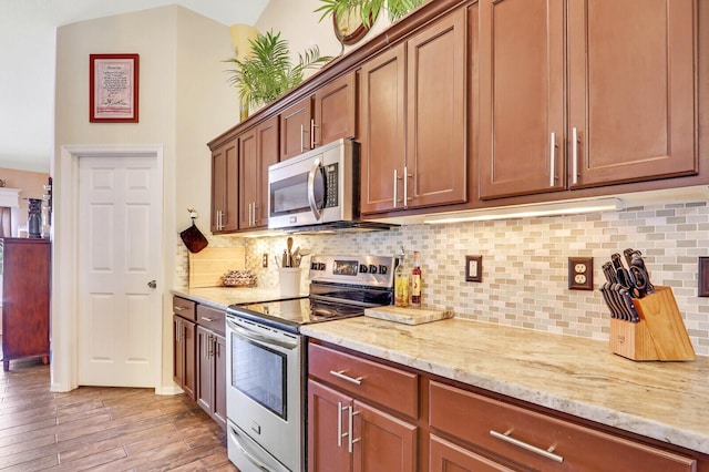 kitchen with light stone countertops, stainless steel appliances, light hardwood / wood-style flooring, and tasteful backsplash