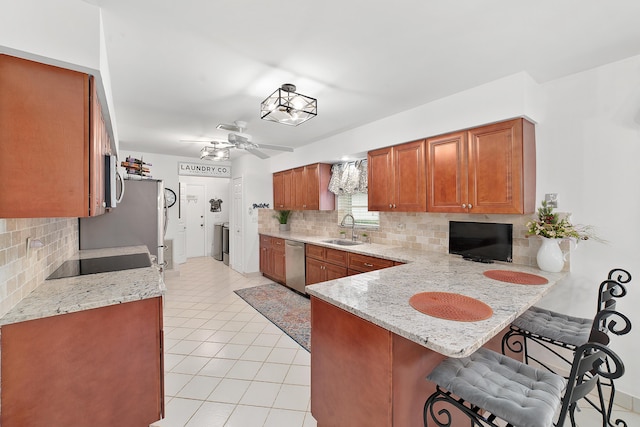 kitchen with a kitchen breakfast bar, sink, tasteful backsplash, kitchen peninsula, and stainless steel appliances