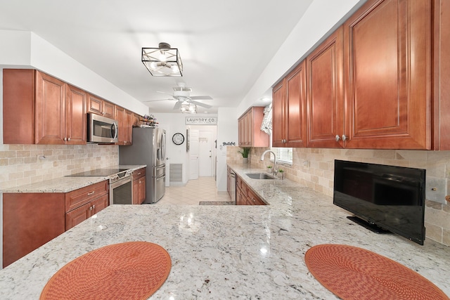 kitchen featuring tasteful backsplash, light stone countertops, sink, and stainless steel appliances