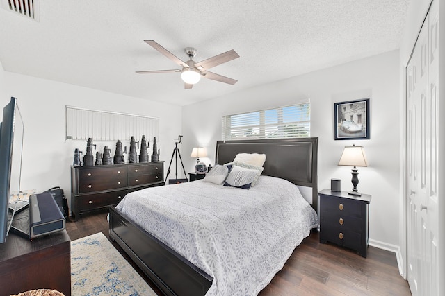 bedroom featuring dark hardwood / wood-style flooring, a textured ceiling, a closet, and ceiling fan