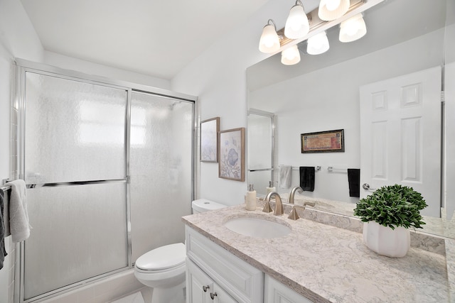 bathroom featuring vanity, a shower with shower door, and toilet