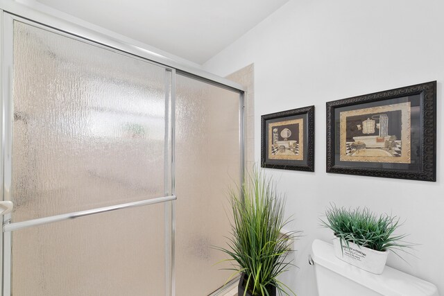 bathroom with a shower with door and toilet