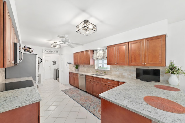 kitchen with light stone countertops, sink, ceiling fan, backsplash, and appliances with stainless steel finishes