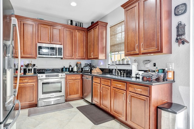 kitchen with appliances with stainless steel finishes, dark stone countertops, and sink