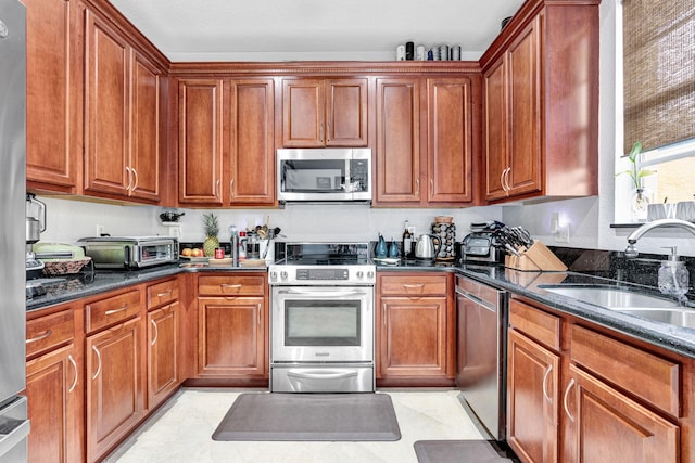 kitchen featuring stainless steel appliances, sink, and dark stone counters