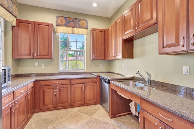 kitchen featuring light stone countertops, dishwasher, and sink