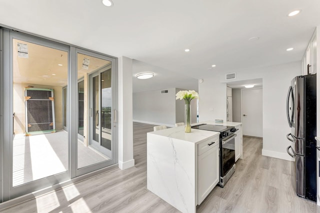 1180 S Ocean Blvd Unit 15B, Boca Raton, FL 33432 - kitchen featuring electric stove, freestanding refrigerator, white cabinets, light stone countertops, and light wood-style floors