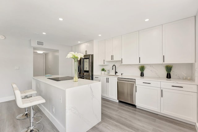 1180 S Ocean Blvd Unit 15B, Boca Raton, FL 33432 - kitchen featuring appliances with stainless steel finishes, a sink, white cabinets, a center island, and light wood-style flooring