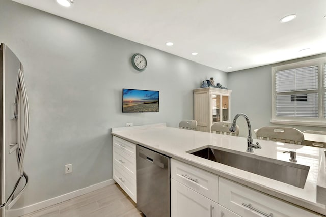 kitchen featuring white cabinets, stainless steel appliances, light stone counters, and sink