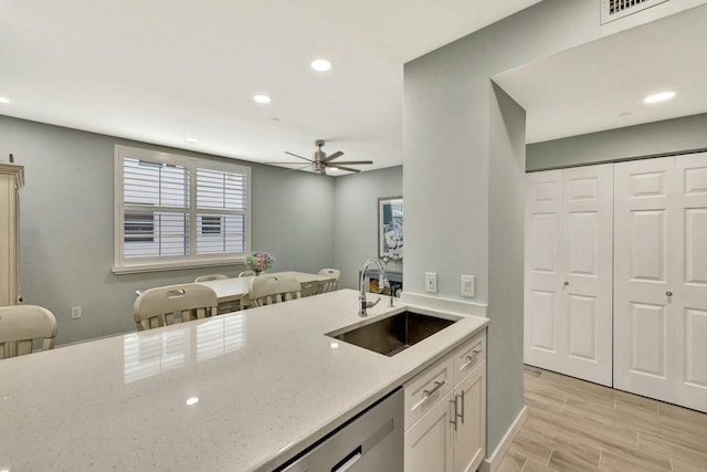 kitchen with white cabinets, sink, stainless steel dishwasher, ceiling fan, and light stone counters