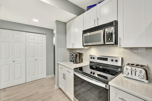 kitchen featuring light wood-type flooring, white cabinetry, and appliances with stainless steel finishes