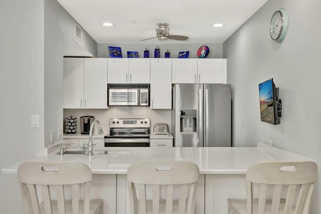 kitchen with a breakfast bar area, kitchen peninsula, white cabinets, and stainless steel appliances