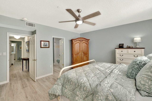 bedroom featuring ceiling fan, a walk in closet, ensuite bathroom, and light hardwood / wood-style flooring