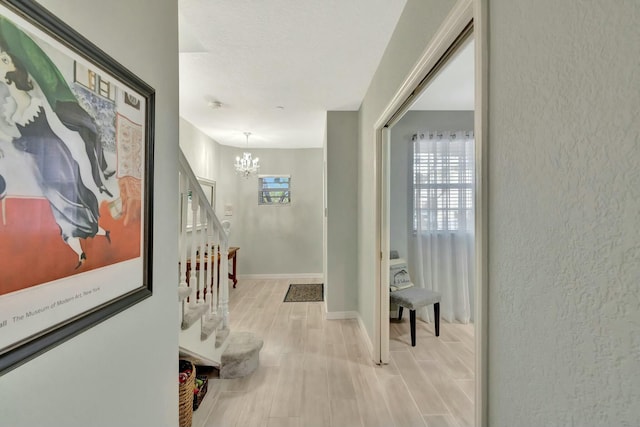 hallway with a chandelier and light hardwood / wood-style floors