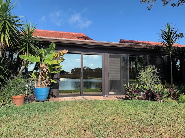 rear view of house featuring a water view and a lawn