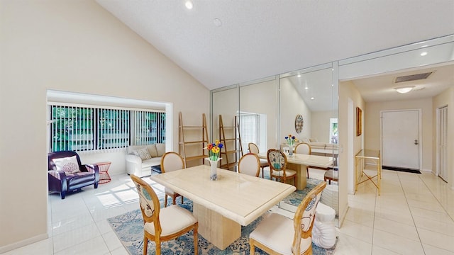 tiled dining space featuring a textured ceiling, a wealth of natural light, and high vaulted ceiling