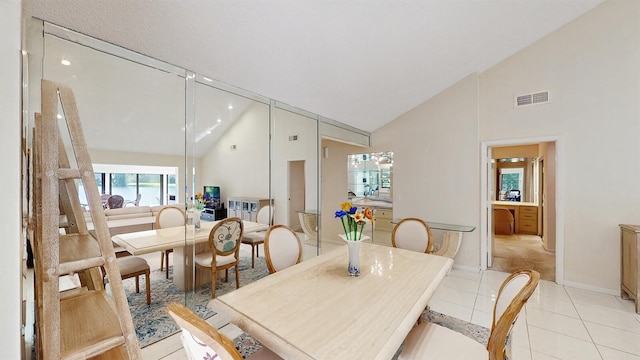 dining area featuring high vaulted ceiling and light tile patterned flooring