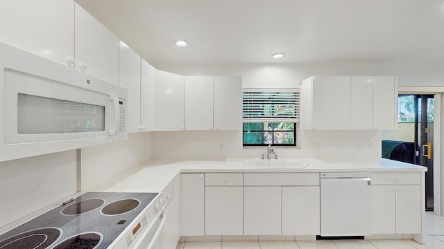 kitchen with light tile patterned floors, sink, white cabinets, and white appliances