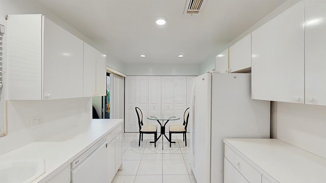 kitchen featuring white cabinets, sink, light tile patterned flooring, and white appliances