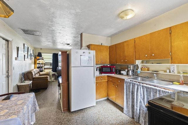 kitchen with stove, white fridge, and sink