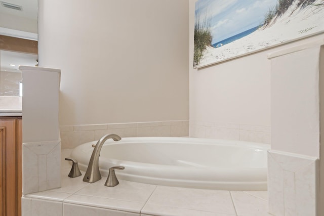 bathroom featuring vanity, a relaxing tiled tub, and tile patterned floors