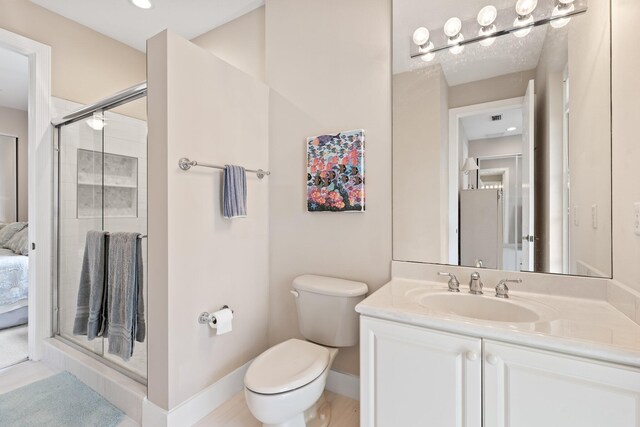 bathroom featuring vanity, a shower with door, and toilet