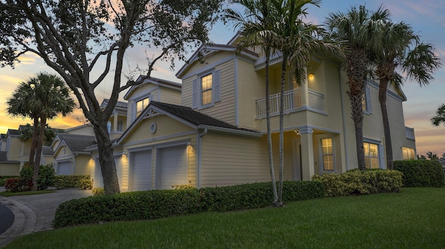 view of front of home with a garage, a balcony, and a lawn