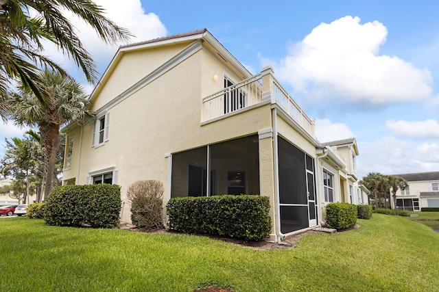 view of property exterior featuring a lawn, a sunroom, and a balcony