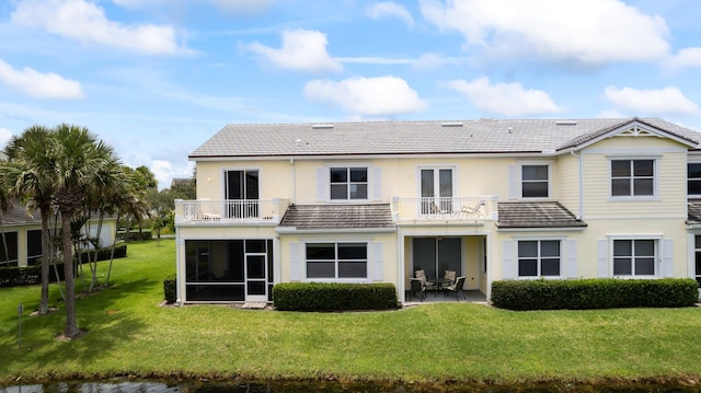 back of property with a balcony, a yard, and a patio