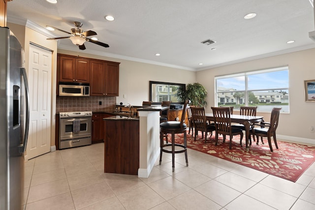 kitchen featuring stainless steel appliances, ornamental molding, and a kitchen bar