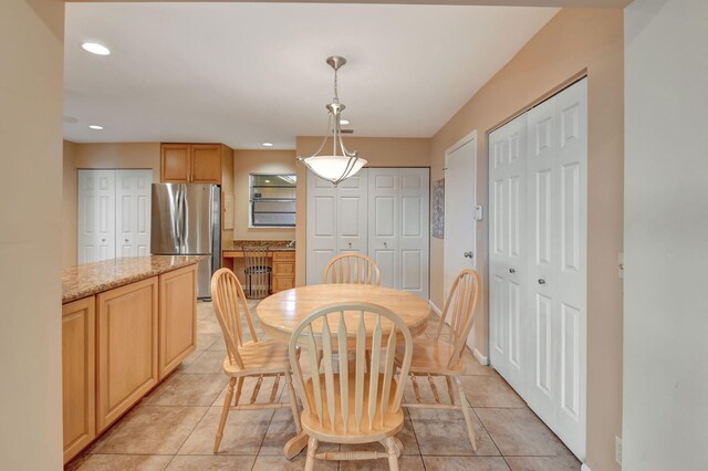 kitchen featuring light stone countertops, stainless steel appliances, light brown cabinetry, hanging light fixtures, and ceiling fan