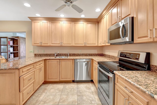 kitchen featuring appliances with stainless steel finishes, light brown cabinetry, sink, kitchen peninsula, and light stone counters