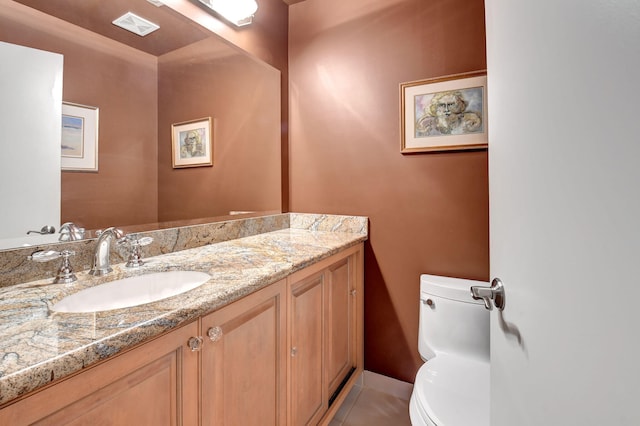 bathroom with toilet, vanity, and tile patterned flooring