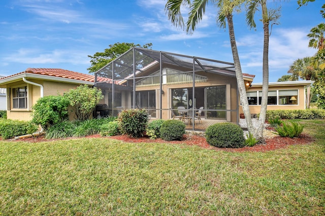 rear view of house with glass enclosure and a yard