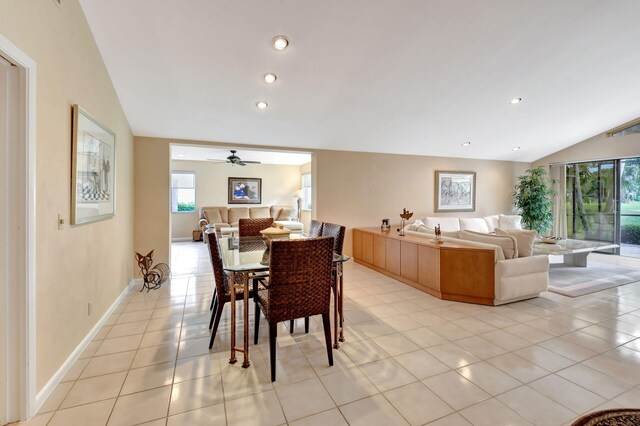 dining area with ceiling fan, light tile patterned floors, and vaulted ceiling