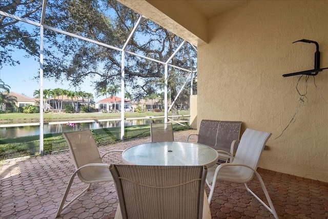 view of patio with a water view and glass enclosure