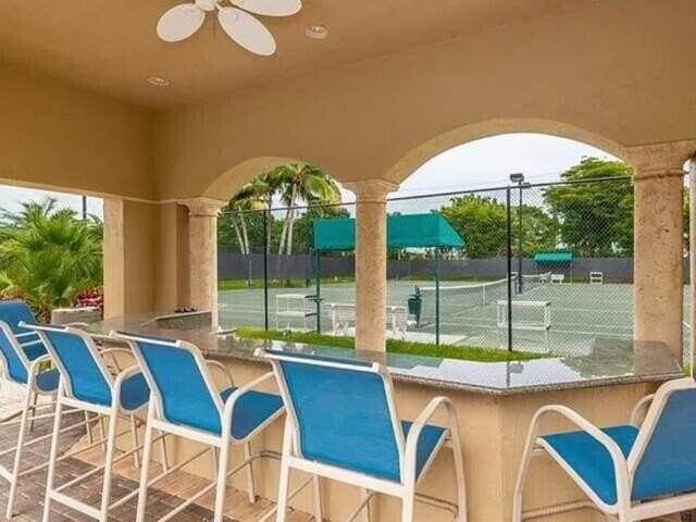 view of patio featuring an outdoor bar, ceiling fan, and tennis court