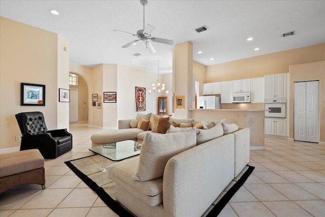 living room with light tile patterned floors, ceiling fan with notable chandelier, and a high ceiling