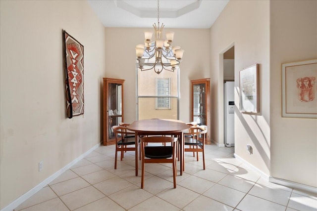 tiled dining room with a raised ceiling and an inviting chandelier