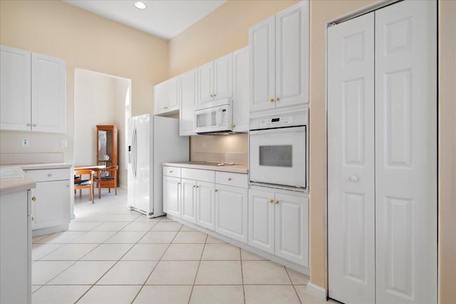 kitchen with white cabinets, white appliances, and light tile patterned flooring