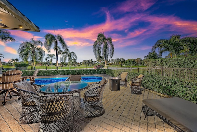 patio terrace at dusk with a fenced in pool