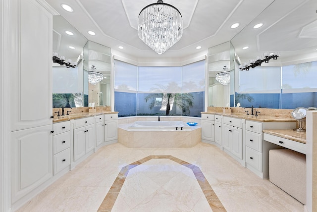 bathroom featuring an inviting chandelier, vanity, and tiled bath